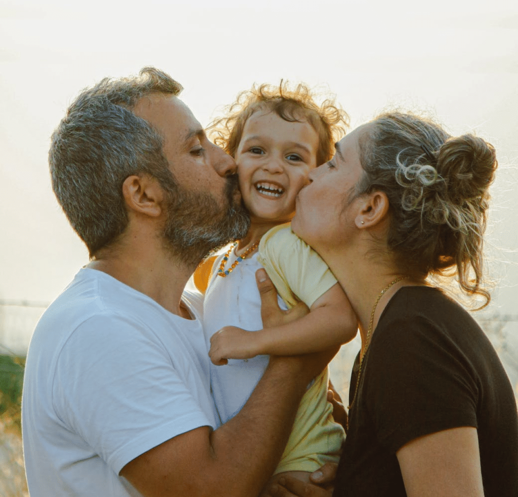 Parents kissing child's cheeks